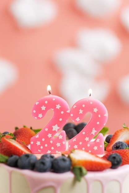 Gâteau d'anniversaire numéro 22 Belle bougie rose en gâteau sur fond rose avec des nuages blancs Gros plan et vue verticale