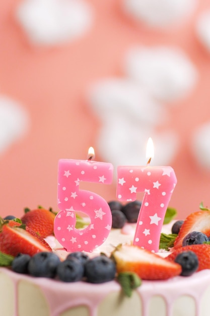 Gâteau d'anniversaire numéro 57 Belle bougie rose en gâteau sur fond rose avec des nuages blancs Gros plan et vue verticale