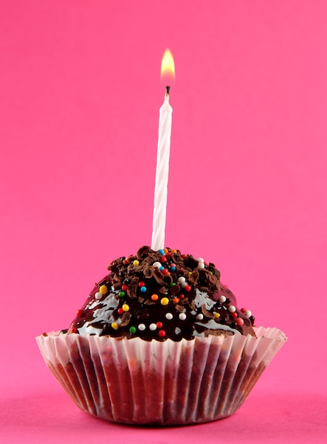 un gâteau d'anniversaire savoureux avec une bougie sur un fond rose