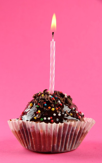 un gâteau d'anniversaire savoureux avec une bougie sur un fond rose