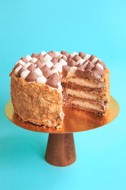 Gâteau d'anniversaire en tranches sur le stand de gâteau en bois. Belle génoise à la crème fouettée. Fond bleu. Espace de copie. Photographie culinaire pour la recette.