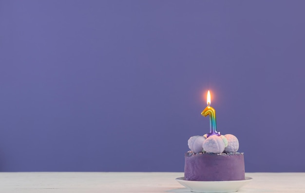 Gâteau d'anniversaire violet avec des bougies allumées sur fond violet