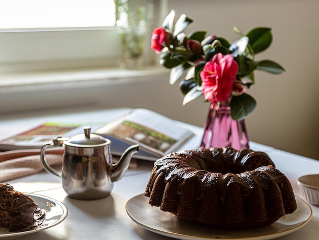 Un gâteau sur une assiette à côté d'un pot de fleurs