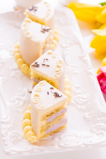 Gâteau au chocolat blanc au miel et à la lavande fait avec une génoise infusée de miel et fourrée de couches de mousse à la lavande, recouverte de chocolat blanc.