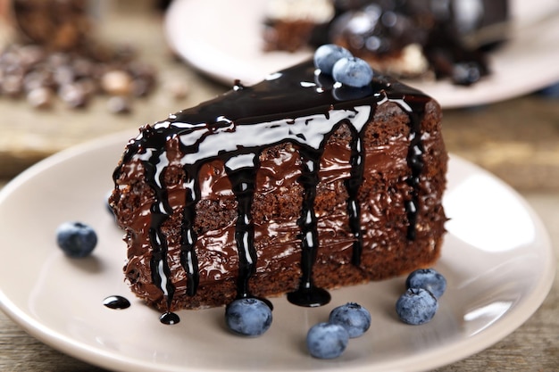 Gâteau au chocolat avec crème au chocolat et bleuets frais sur plaque sur fond de bois