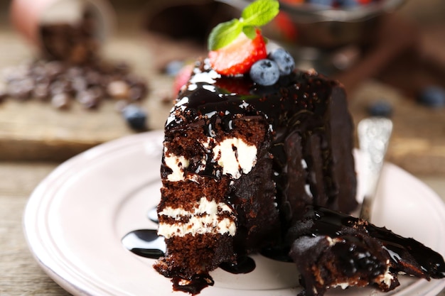 Gâteau au chocolat avec de la crème et des baies fraîches sur une assiette sur fond de bois