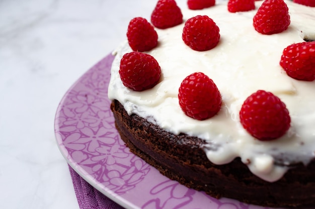 Gâteau au chocolat avec crème sur le dessus et framboises