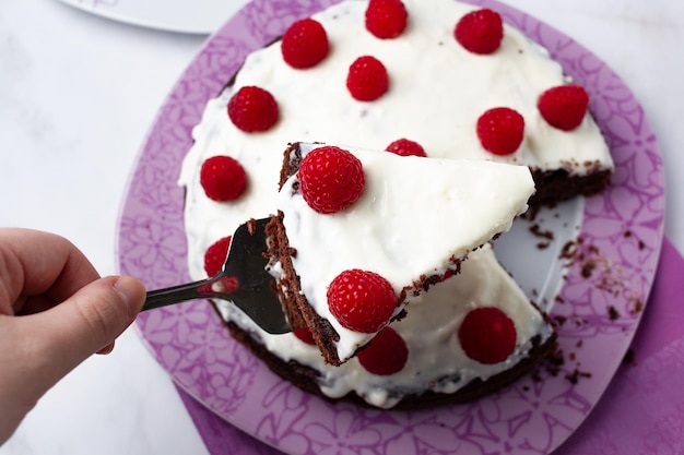 Gâteau au chocolat avec crème sur le dessus et framboises