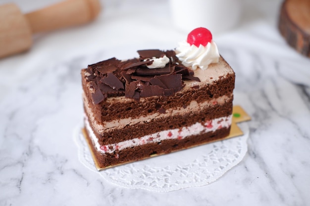 Gâteau au chocolat avec crème fouettée et cerises sur fond de marbre blanc