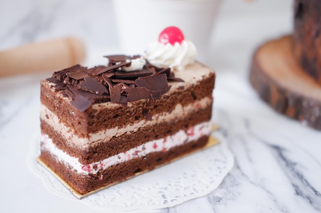 Gâteau au chocolat avec crème fouettée et cerises sur fond de marbre blanc