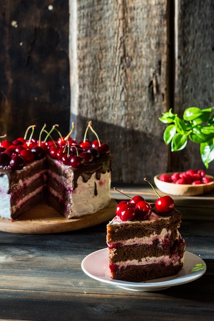 Gâteau au chocolat avec crème fouettée. Gâteau aux cerises au chocolat. Framboise dans une assiette en bois.