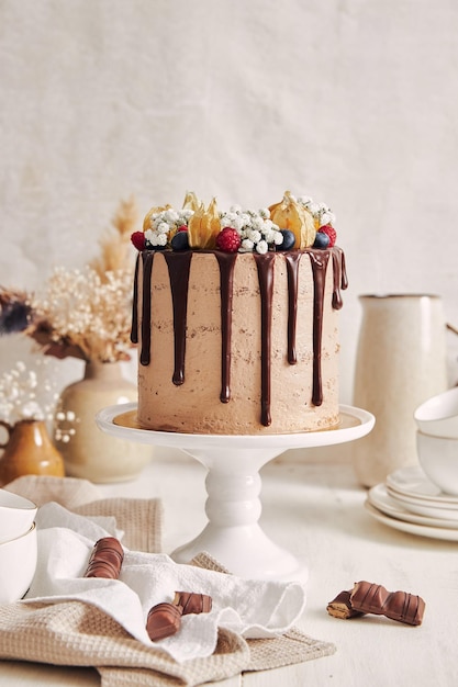 Gâteau au chocolat avec des décorations complexes et des bonbons autour d'elle sur une table en bois blanc