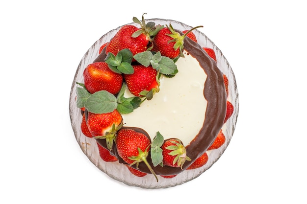 Gâteau au chocolat décoré de fraises fraîches sur une plaque de verre isolée sur fond blanc