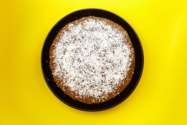 Gâteau au chocolat décoré de noix de coco en flocons sur jaune