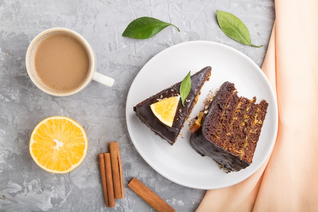 Gâteau au chocolat fait maison à l'orange et à la cannelle avec une tasse de café sur une surface en béton gris. vue de dessus.