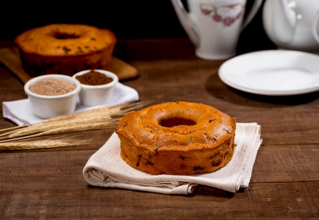 Gâteau au chocolat et à la farine de blé sur tissu sur bois avec gâteau en arrière-plan avec branche de blé, assiette blanche, bootle blanc à côté.