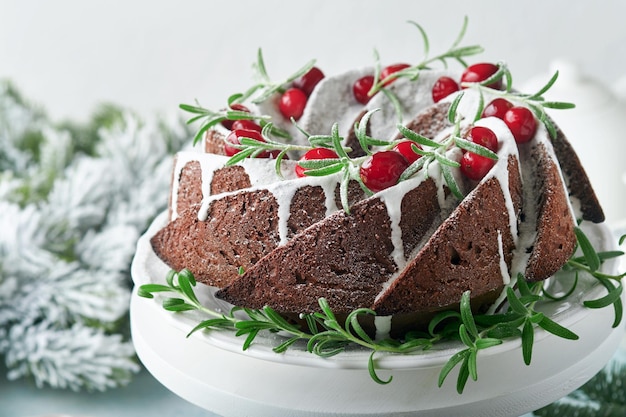 Gâteau au chocolat de Noël Gâteau aux fruits de Noël traditionnel avec canneberges à glaçage blanc et romarin sur un support blanc avec décoration de Noël Cuisson d'hiver à Noël ou au Nouvel An Espace de copie