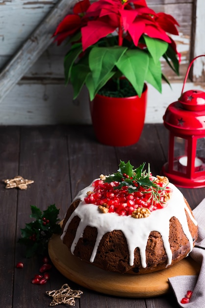 Gâteau au chocolat de Noël avec glaçage blanc et noyaux de grenade un bois sombre avec lanterne rouge et poinsettia