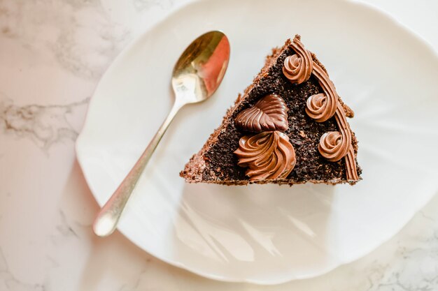 Photo gâteau au chocolat noir sur une assiette blanche et tasse de thé en or jaune. mise au point sélective. dessert sucré. concept saisonnier et vacances