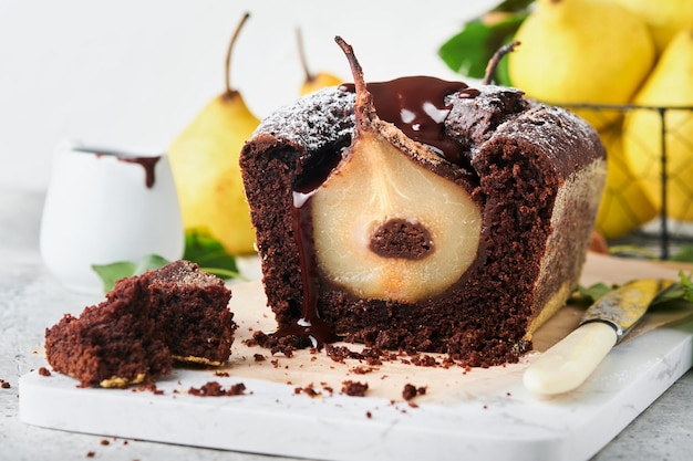 Gâteau au chocolat avec poires cuites à l'intérieur Gâteau aux poires au chocolat ou gâteau au chocolat noir avec poire sur une table gris clair à la maison Concept de recettes de cuisine et de pâtisserie Mise au point sélective