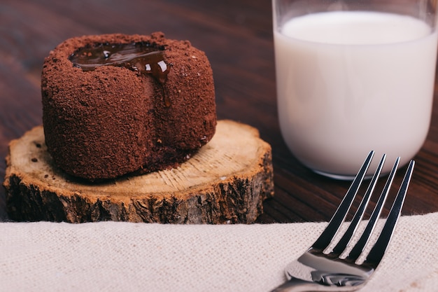 Gâteau au chocolat et verre de lait sur une table brune, fourchette sur la nappe