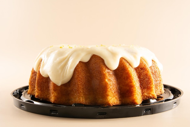 Gâteau au citron classique avec un glaçage laiteux crémeux avec de la croûte de citron sur un fond rose