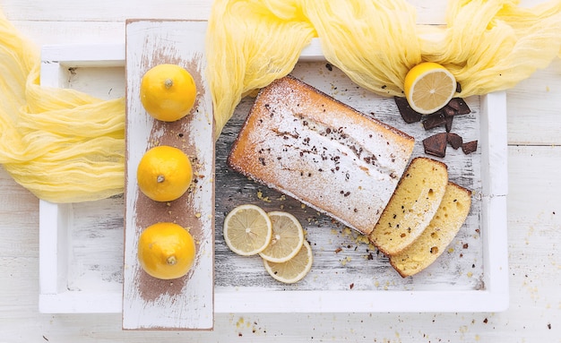 Gâteau au citron avec des fruits sur une surface en bois blanche