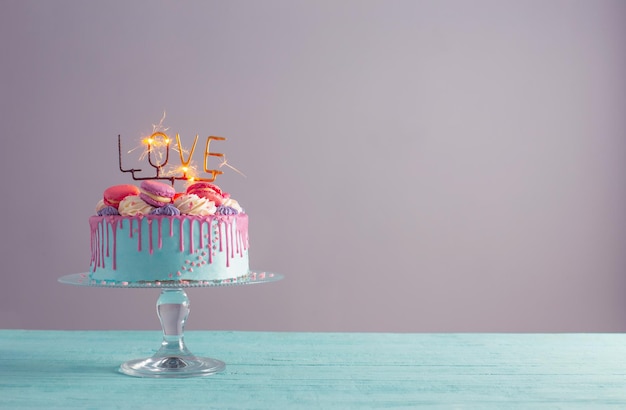 Gâteau au décor rose et bleu et cierge magique brûlant avec texte love