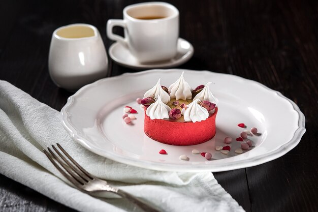 Gâteau au fromage au caramel avec crème et fleurs sur le fond en bois. Une tasse de café et un gâteau sur une assiette blanche