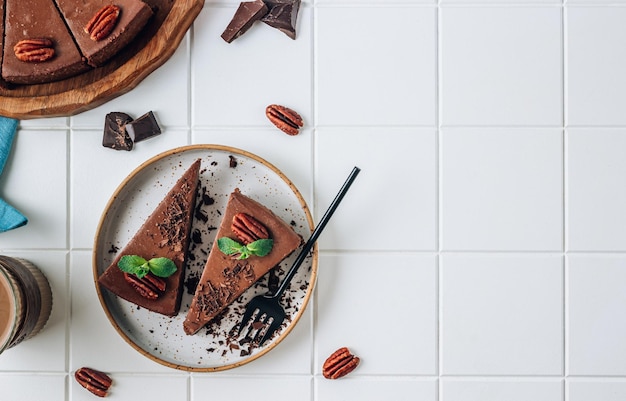 Gâteau au fromage au chocolat avec noix de pécan et tasse de café à la menthe sur fond blanc Vue de dessus avec espace de copie