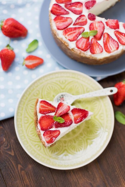 Gâteau au fromage aux fraises fraîches et à la menthe Délicieux gâteau à la crème blanche aux baies rouges et aux feuilles de menthe verte sur une assiette