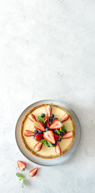 Gâteau au fromage classique à la menthe aux fraises et aux bleuets sur la table grise Écran large Mise à plat Copier l'espace