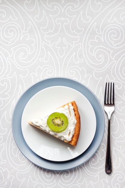 Gâteau au fromage cottage fait maison avec des kiwis et de la crème sur une plaque