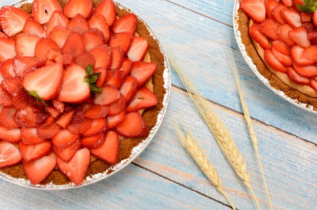 Gâteau au fromage décoré de fraises sur une table en bois bleue