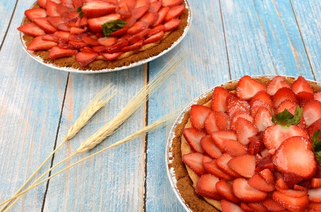 Gâteau au fromage décoré de fraises sur une table en bois bleue