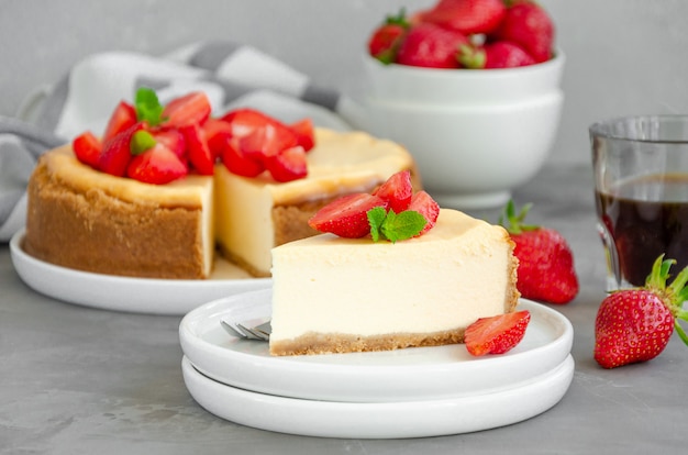 Gâteau au fromage fait maison avec des fraises fraîches sur une plaque blanche