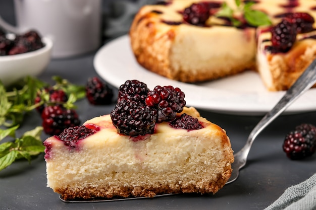 Gâteau au fromage fait maison avec des mûres avec un morceau de gâteau coupé