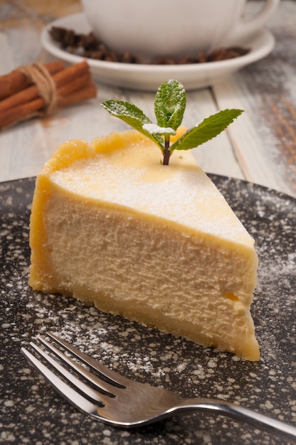 Gâteau au fromage frais à la main sur une plaque sombre avec une feuille de menthe