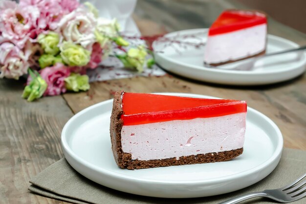 Gâteau au fromage à la gelée rouge dessert sucré avec bouquet de fleurs sur fond de table en bois cadeau à la femme le 8 mars vacances saint valentin petit déjeuner nourriture journée internationale de la femme