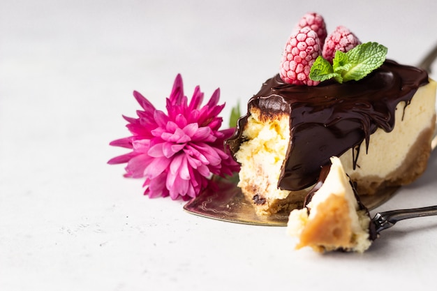 Gâteau au fromage à la new-yorkaise avec glaçage au chocolat, framboises et menthe. Concept de la Saint-Valentin.