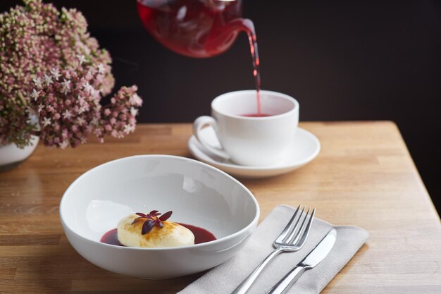 Gâteau au fromage avec sauce aux baies et verser du thé rouge sur fond. table du matin du petit déjeuner avec des fleurs. Crêpes Cottage Cheese.