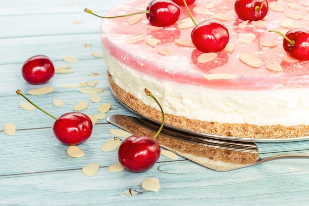 Gâteau au fromage sucré en gros plan, cerises éparses sur une surface en bois clair