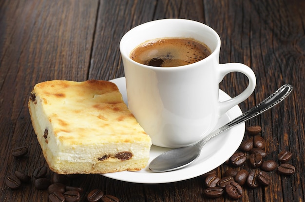 Gâteau au fromage avec une tasse de café chaud sur une table en bois foncé