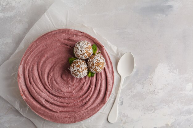 Gâteau au fromage végétalien cru aux baies roses et au caramel avec des boules crues sucrées à la noix de coco, vue de dessus. Concept de nourriture végétalienne saine.