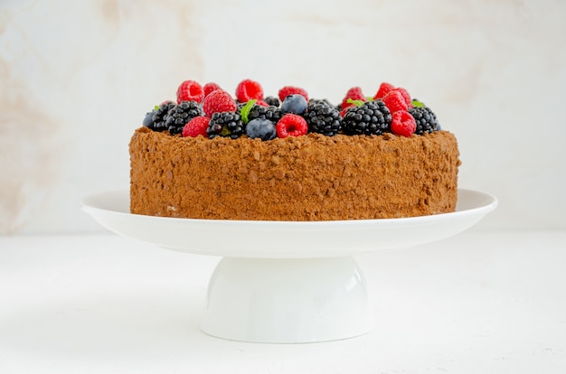 Gâteau au miel et au chocolat avec de la crème et des baies fraîches. Copiez l'espace.