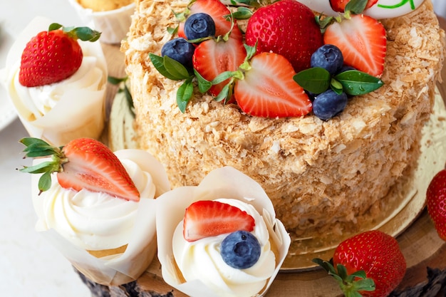 Gâteau au miel décoré de fraises et bleuets lumineux.