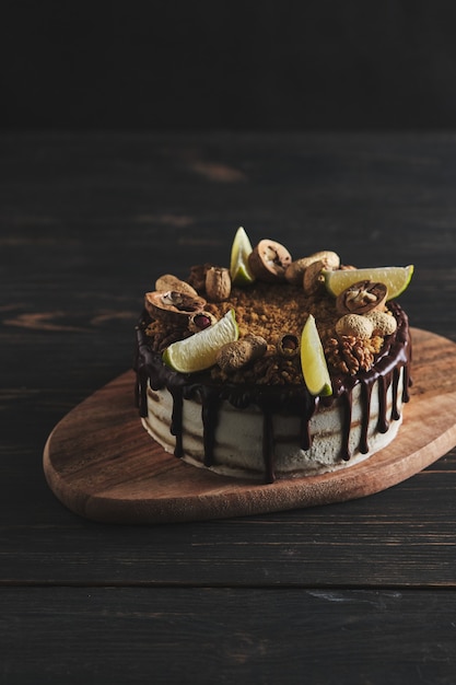 Gâteau au miel maison classique. Un gâteau d'anniversaire avec du miel, du chocolat, des noix et du beurre de noix. Dessert sur une planche de bois.