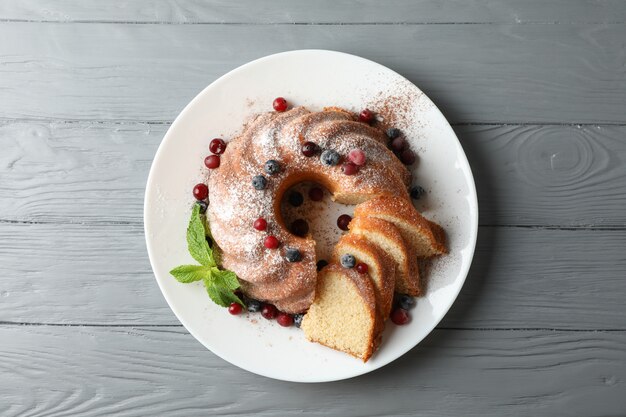 Gâteau au sucre en poudre, baies et menthe sur fond de bois