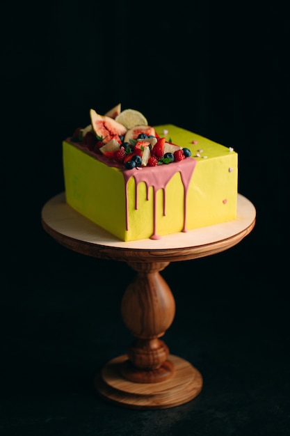 Gâteau aux agrumes jaune décoré de figues, framboises, myrtilles et citron.