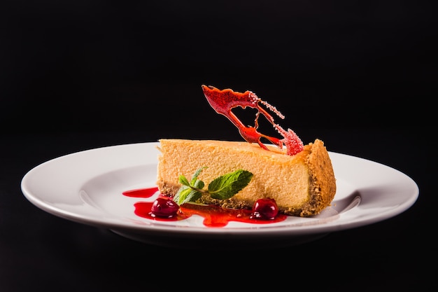 Gâteau aux baies avec décoration sur une plaque blanche ronde sur fond noir